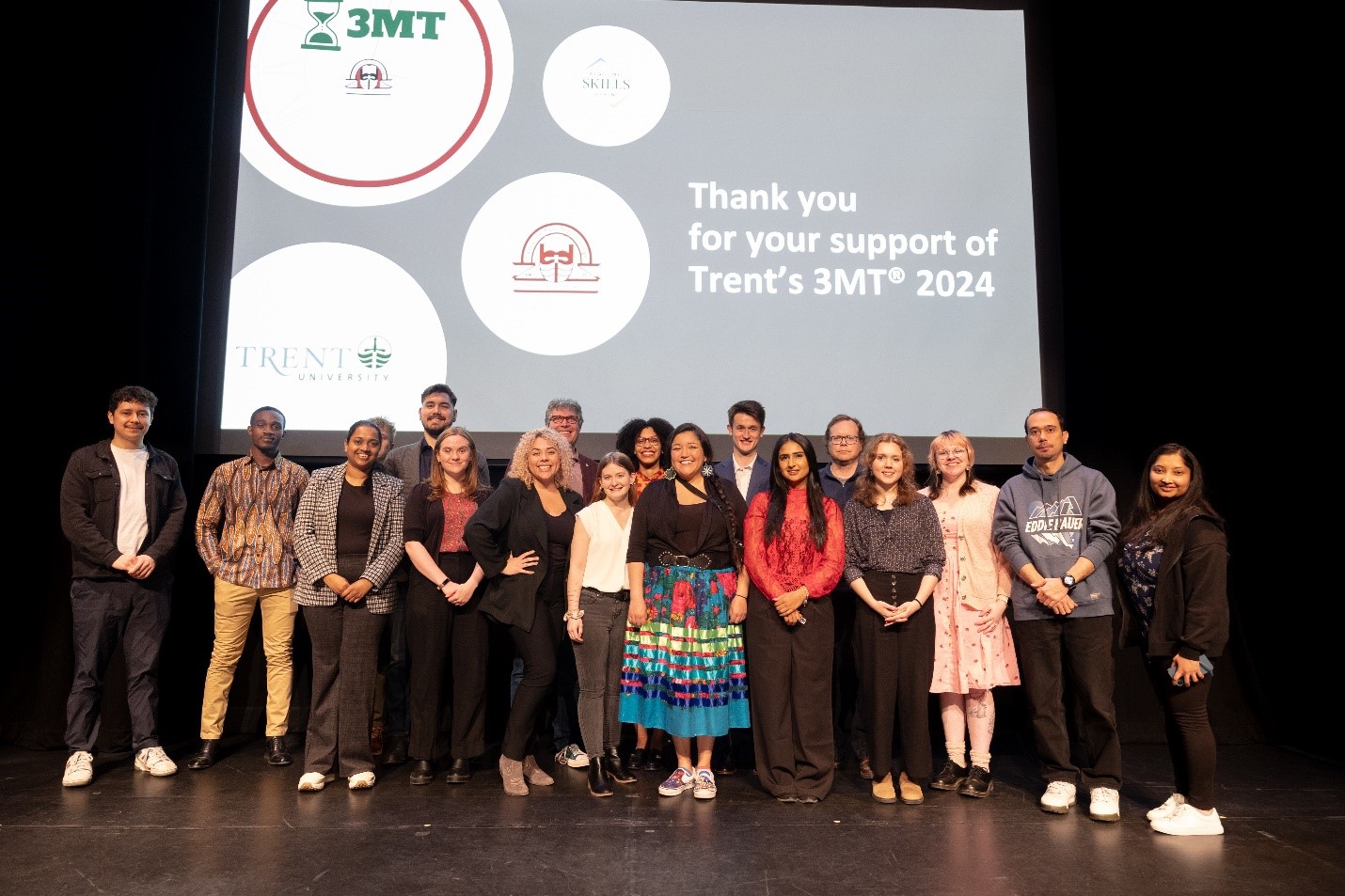 Photo of all the participants in Trent’s 2024 3MT® on stage at Market Hall, Peterborough.