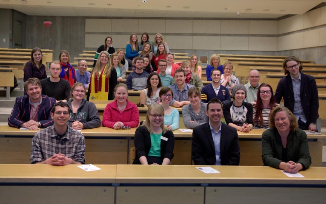 A group of students and faculty in a Gzowski classroom after a lecture.