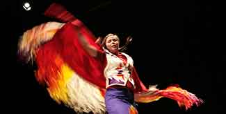 INdigenous student dancing on stage against a black backdrop