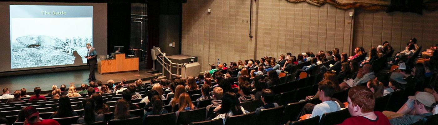 A professor talking to a full class in Wenjack theater