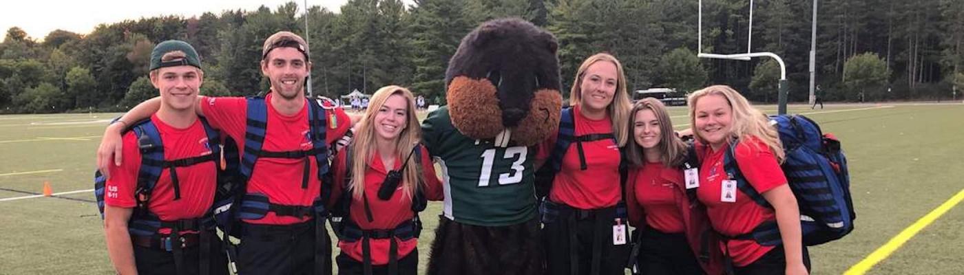 Students on an athletic field posing with a beaver mascot.