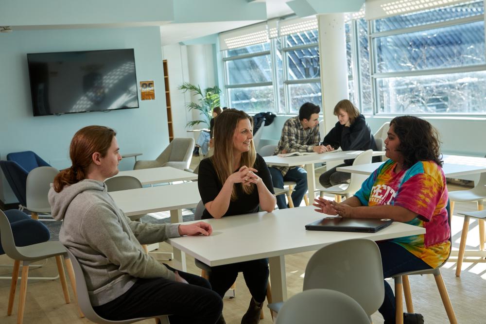 A group of students sit around a table together in the Otonabee College Commons