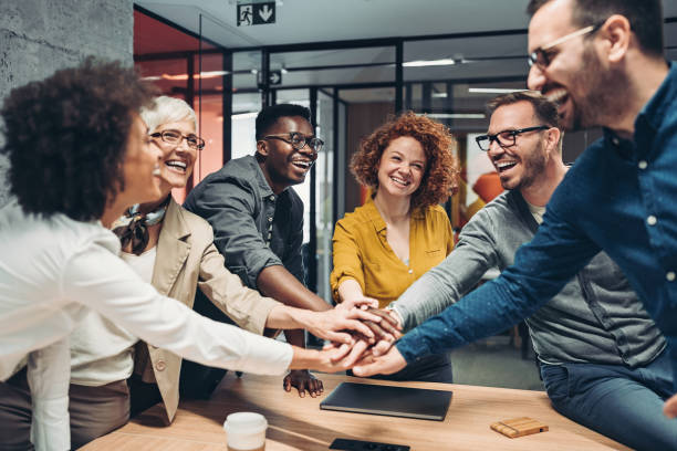 group of people in an professional environment with their hands in the middle for a team huddle.