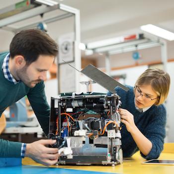 a guy and girl concentrating on building a robot