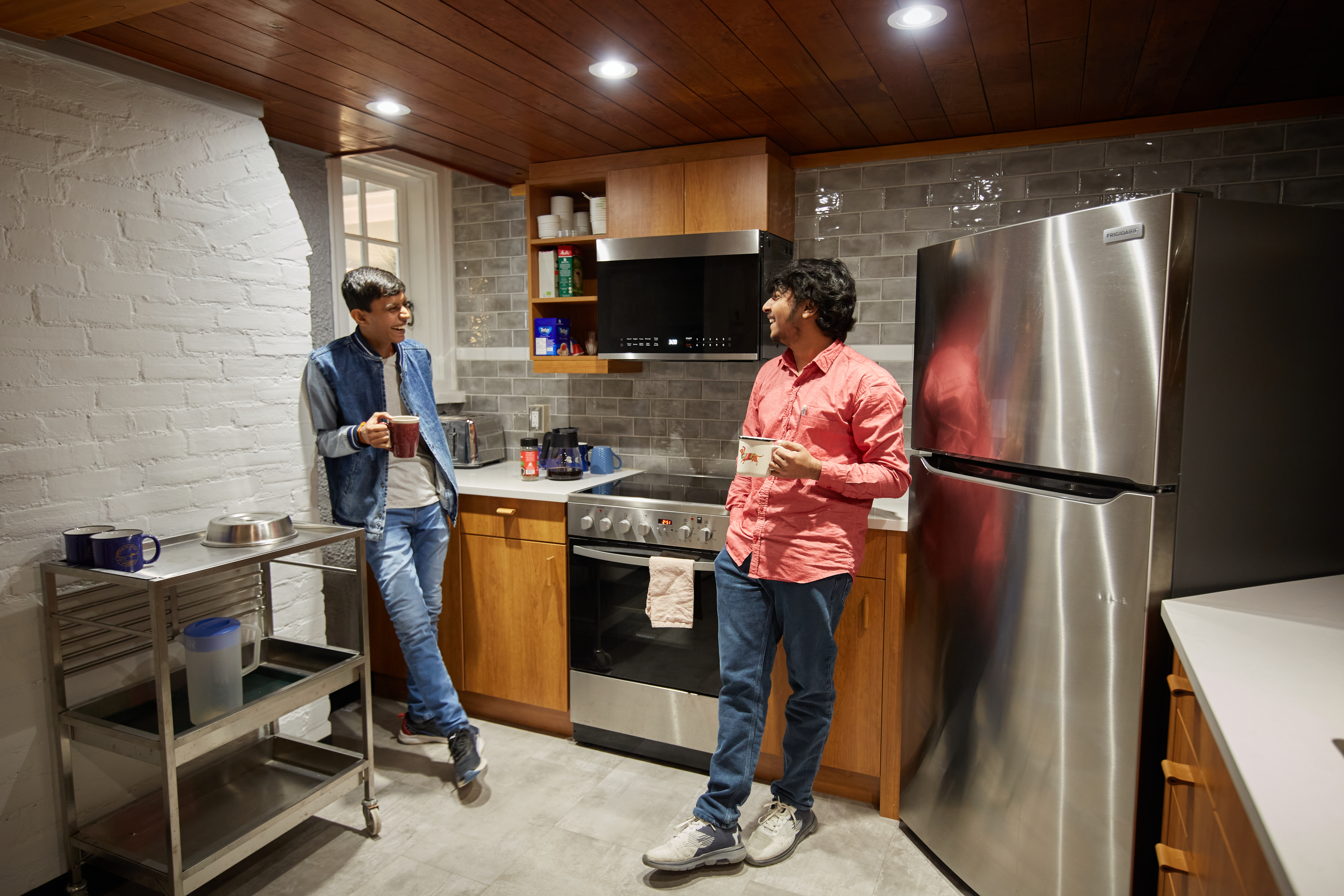 Photo of two students in kitchen holding mugs