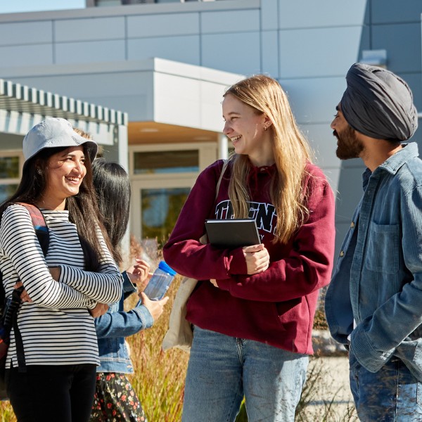 Three students have a conversation on campus