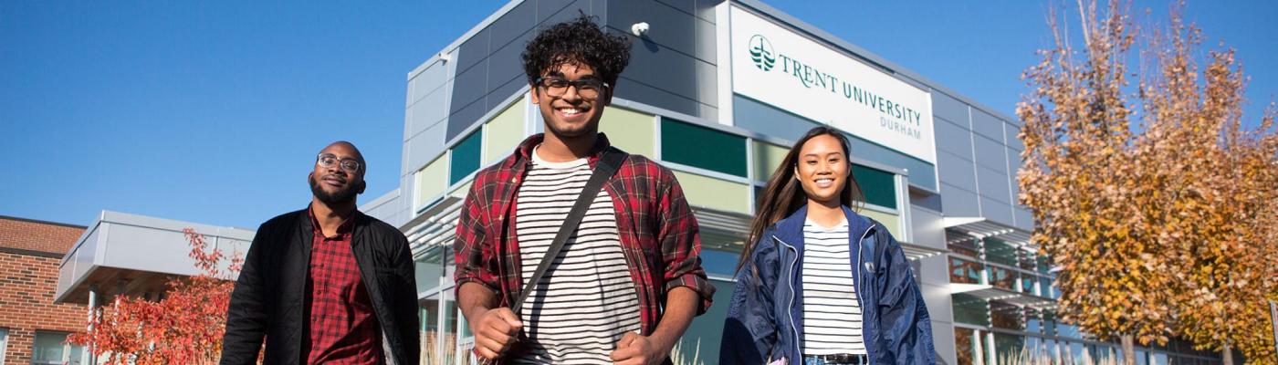 Three students posing outside of the Trent Building A