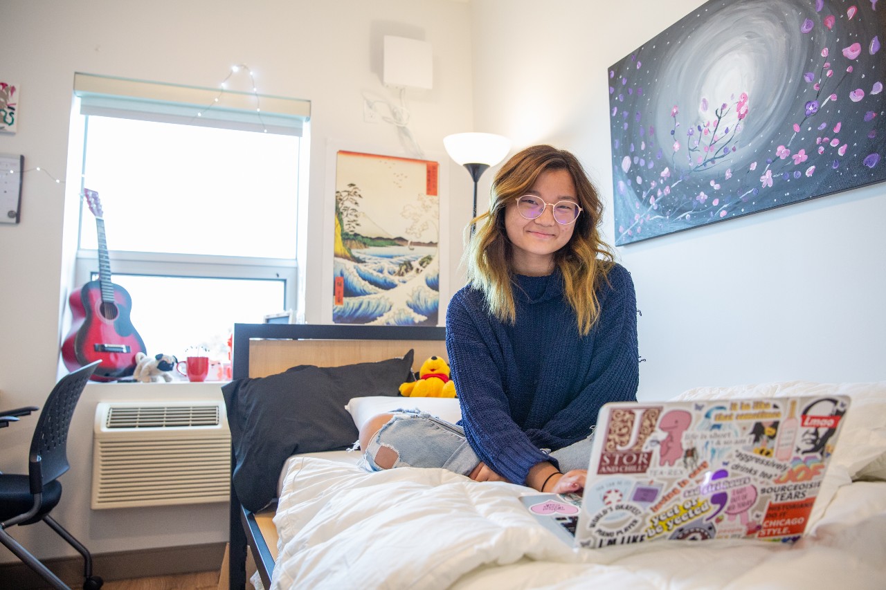 A student sitting on her bed in residence