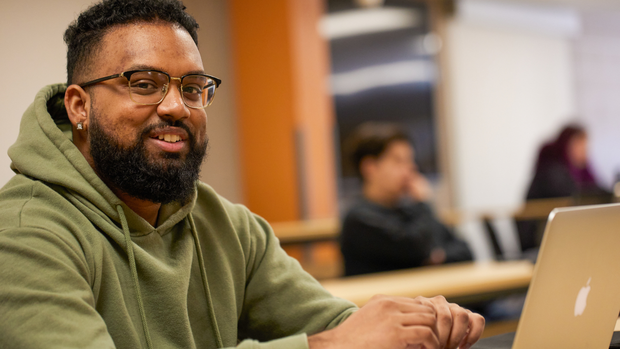 A student with a laptop smiling