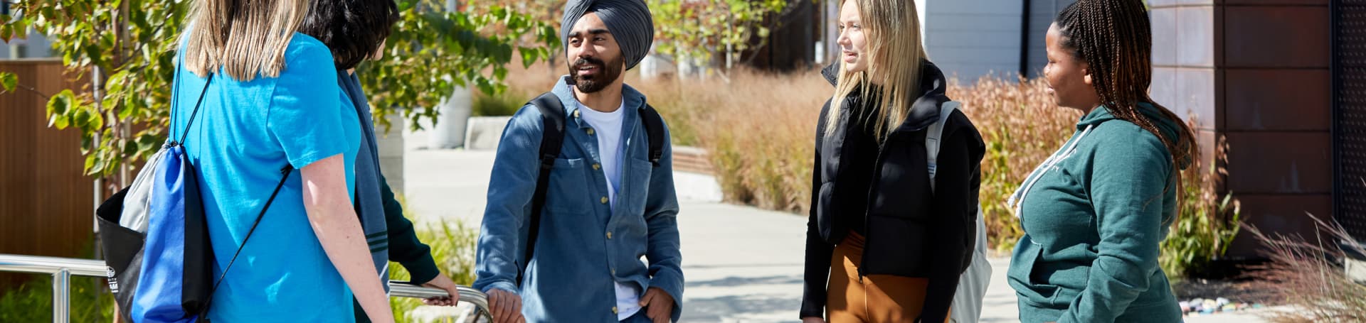 Diverse group of university students talking outdoors on campus