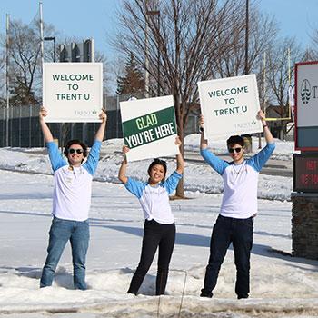Trent University Durham students holding up welcome signs outside of the campus open house event.