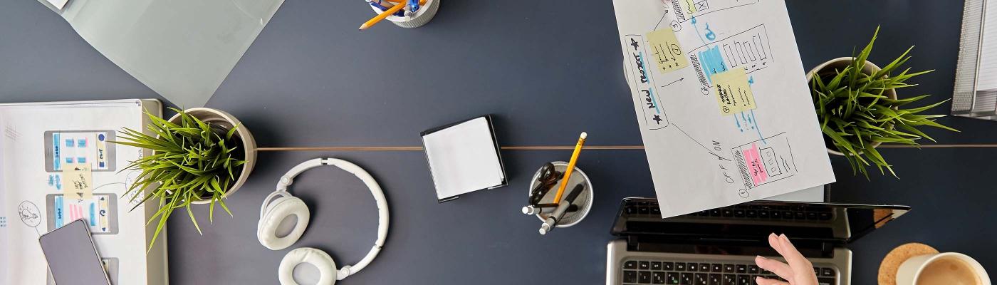 Aerial view of table, messy with notes, laptops and people's hands