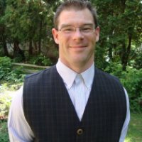 graduate student Chad Cuss smiling at camera wearing a vest and collared shirt