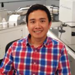 Doctor Huy Dang smiling in a chemistry lab