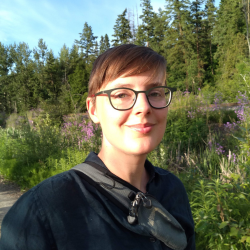 Anne Pasek smiling in front of a forested background