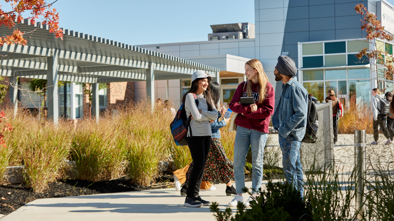 Three Trent Durham students talking to each other outside of building A.