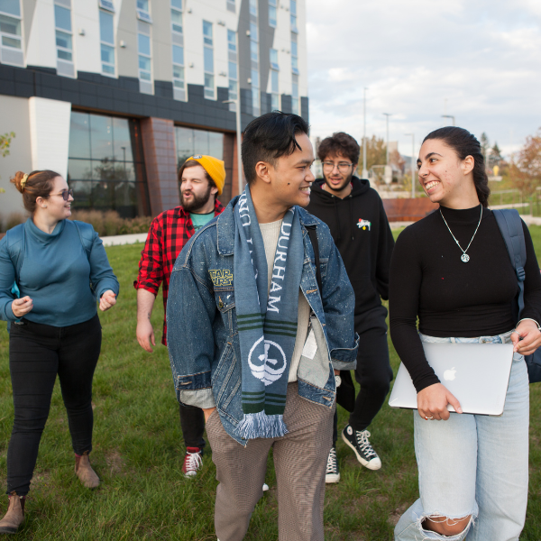 Group of Trent Durham students walking outside of building B, smiling and talking. 