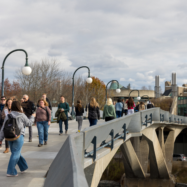 Groups of students and their families walking across the Faryon bridge during open house.