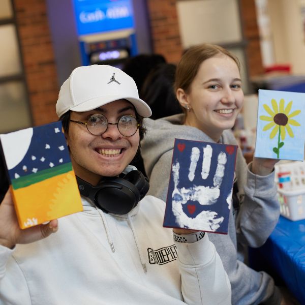 Two students showing off crafts they have painted