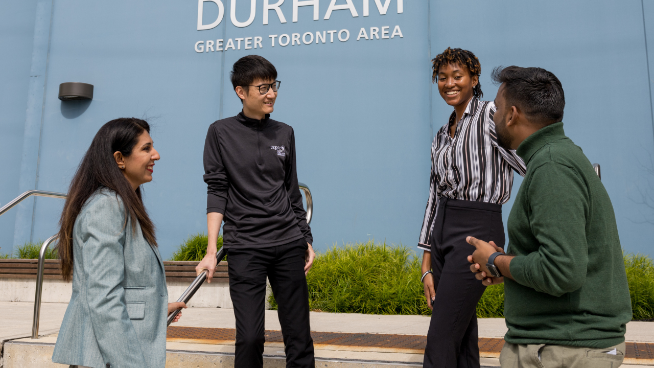 Four Trent graduate studies students, talking outside of Trent Durham GTA building B.