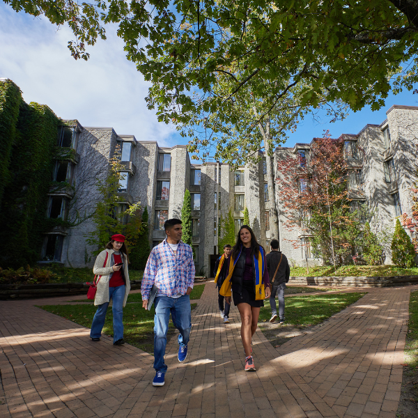 Trent University students walking out from Champlain College, in the quad, talking. 