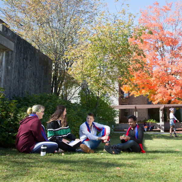 A group of Trent students sitting on Champlain College’s quad, talking. 