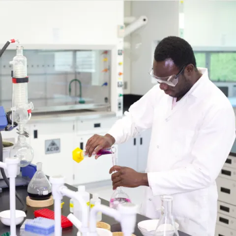 Trent University student in lab handling chemicals. 