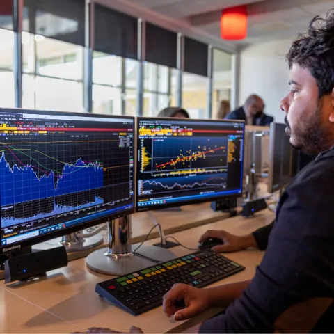 Trent University student in data science seminar, using computer that displays stocks.