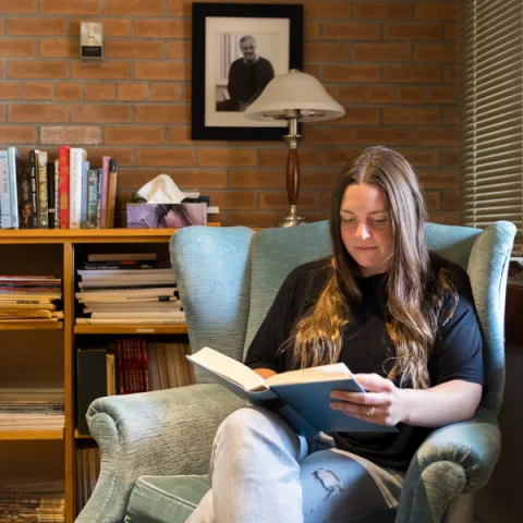 Trent University student reading a book in Traill College.