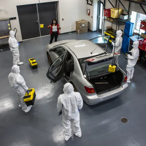 Trent University Forensics science students and professor in garage lab car.