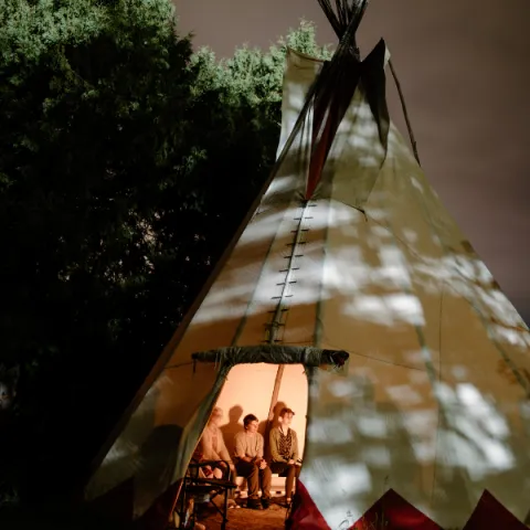 Trent University student and staff inside of a tipi at night.