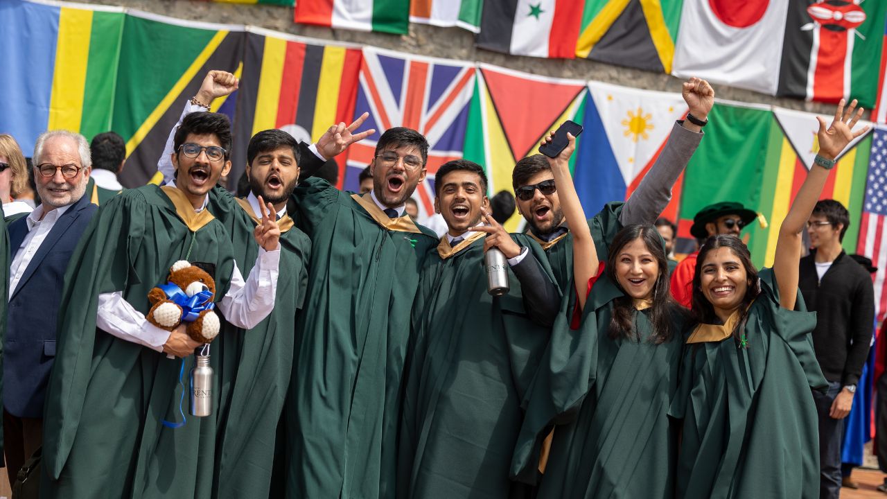 Graduating students infront of wall of world flags