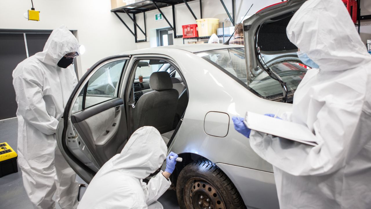 Three students inspecting a car