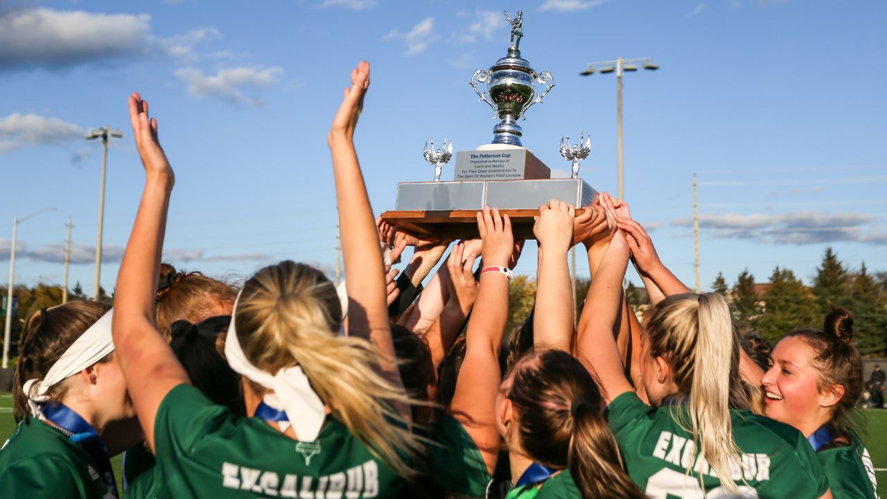 Women's lacrosse celebrating with a trophy