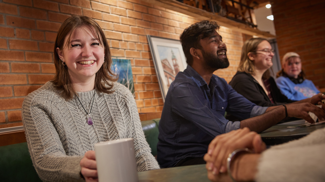 Student in the Trend, holding a coffee mug and smiling at the camera.