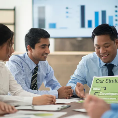 A group of business accountants in a meeting, talking and looking at papers.