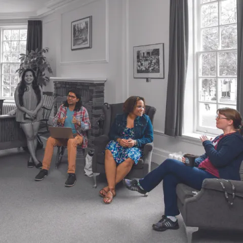 A group of Trent University students and staff, talking in common room.