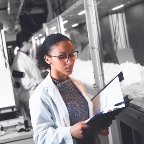 A Trent University student looking at a clip board, in a lab.