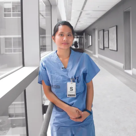 Image of a nurse in a hallway, looking at the camera.