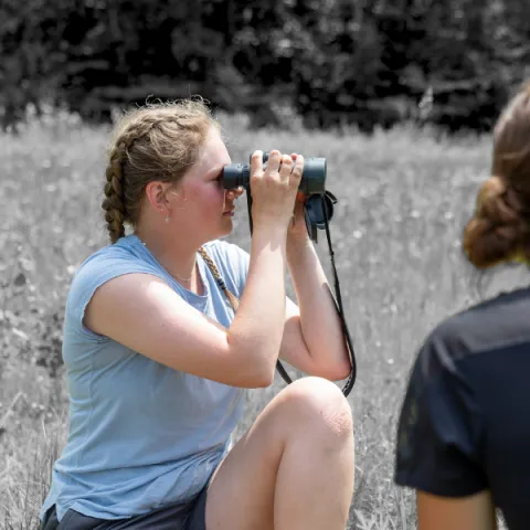 Trent University students surveying land with binoculars.