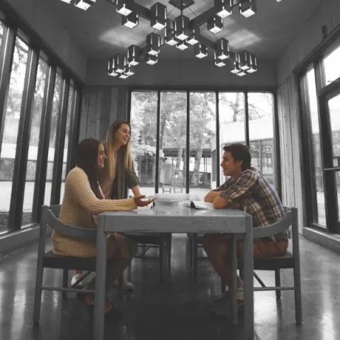 Trent University students sitting at a table, talking with each other.