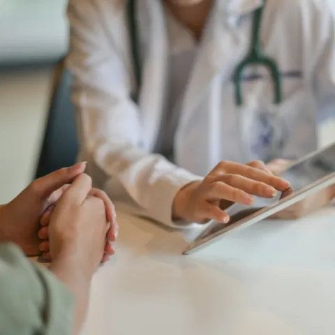 Doctor showing a patient some information on a digital tablet.