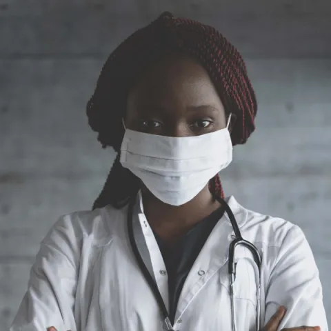 Image of a nurse with a mask on, looking at the camera