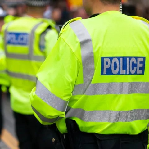 Police in high visibility jackets in front of crowds at an event.