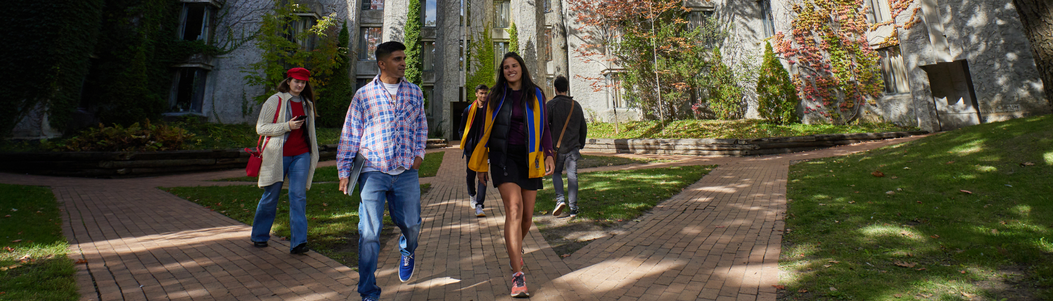 Trent University students walking out from Champlain College, in the quad, talking.