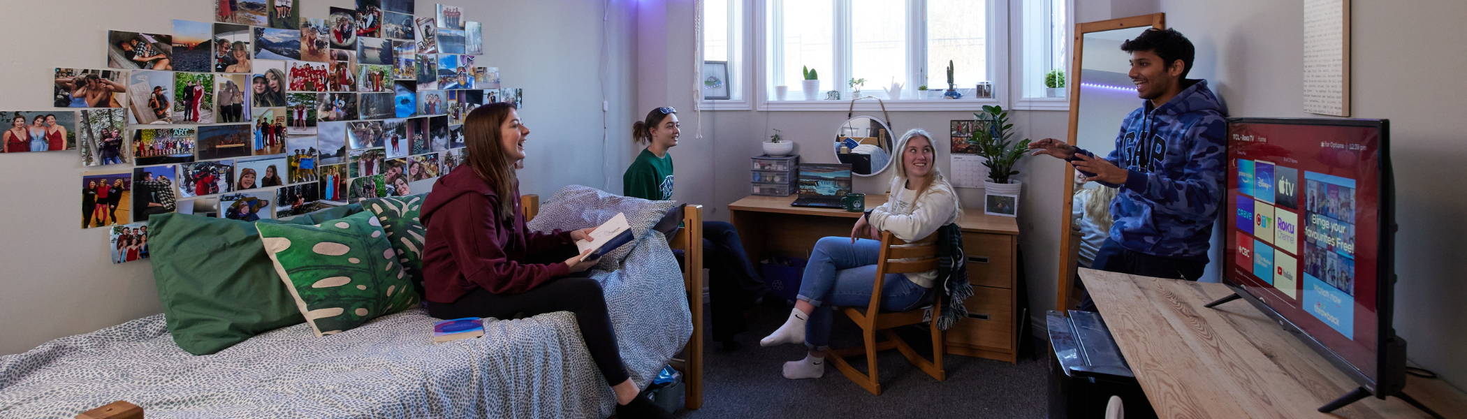 A group of Trent University students sitting in annex bedroom, talking.