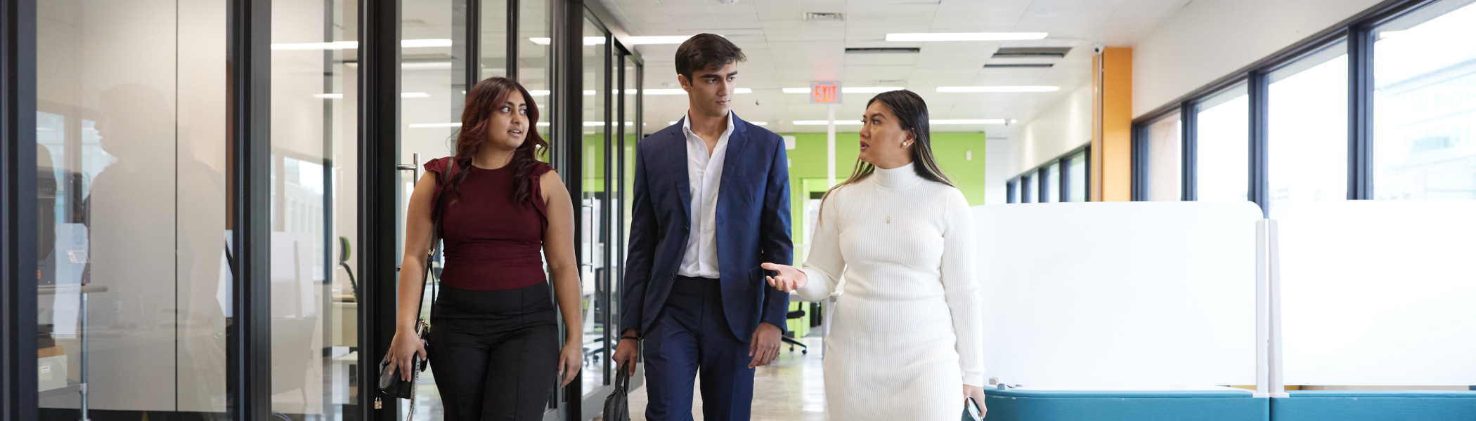 Three Trent University Business Administration students walking down a business hallway in their co-op placement.