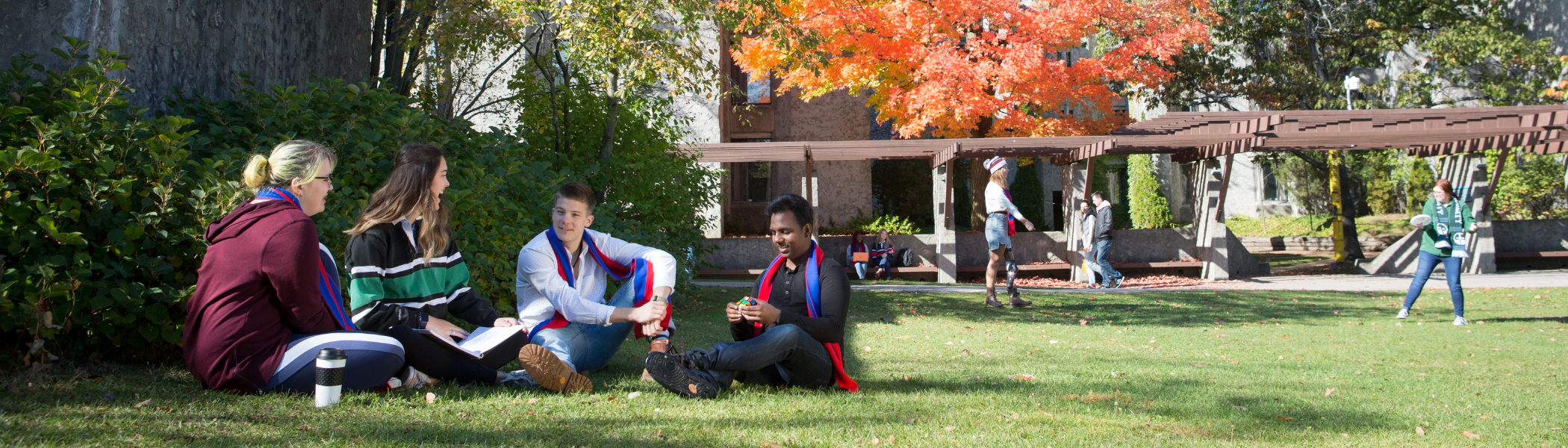 A group of Trent students sitting on Champlain College’s quad, talking.