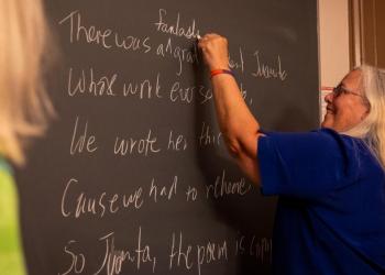 Graduate teaching assistant writing on a blackboard