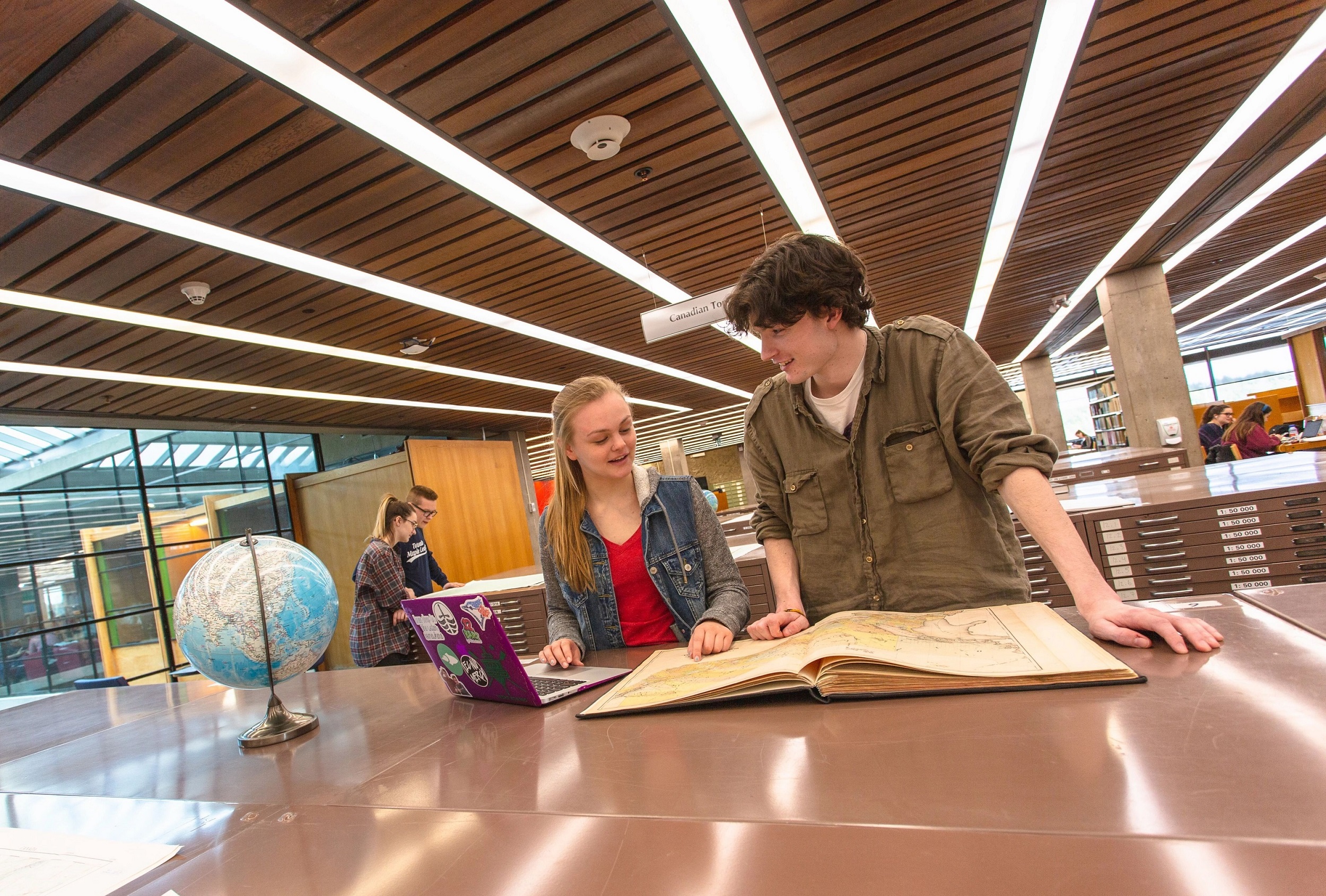  Two students reading an atlas together.